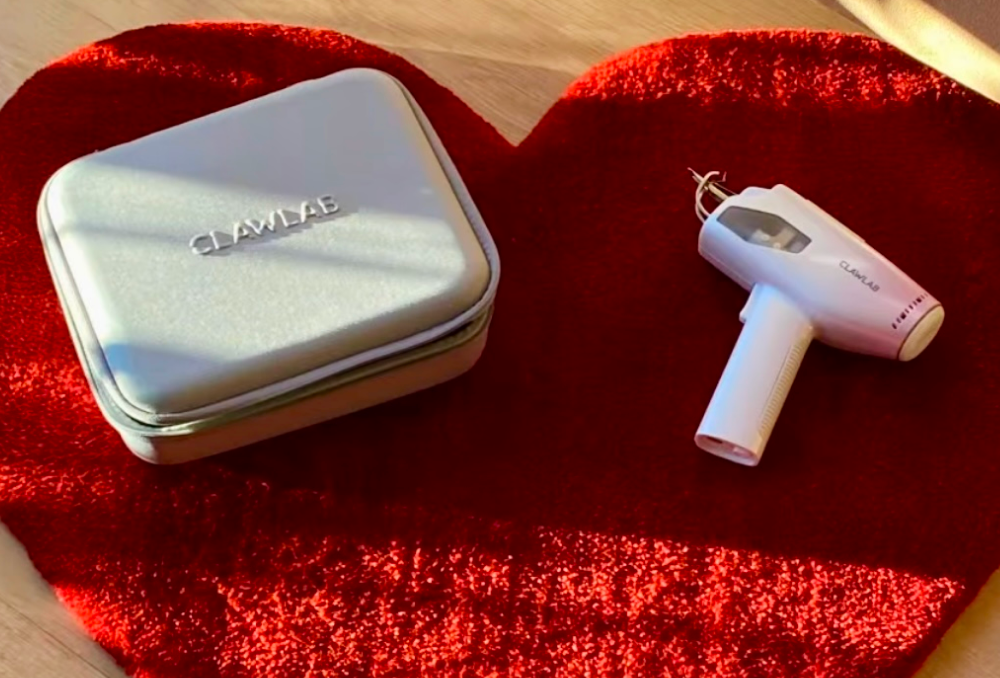 Clawlab tufting gun and its gray carrying case placed on a red heart-shaped rug.