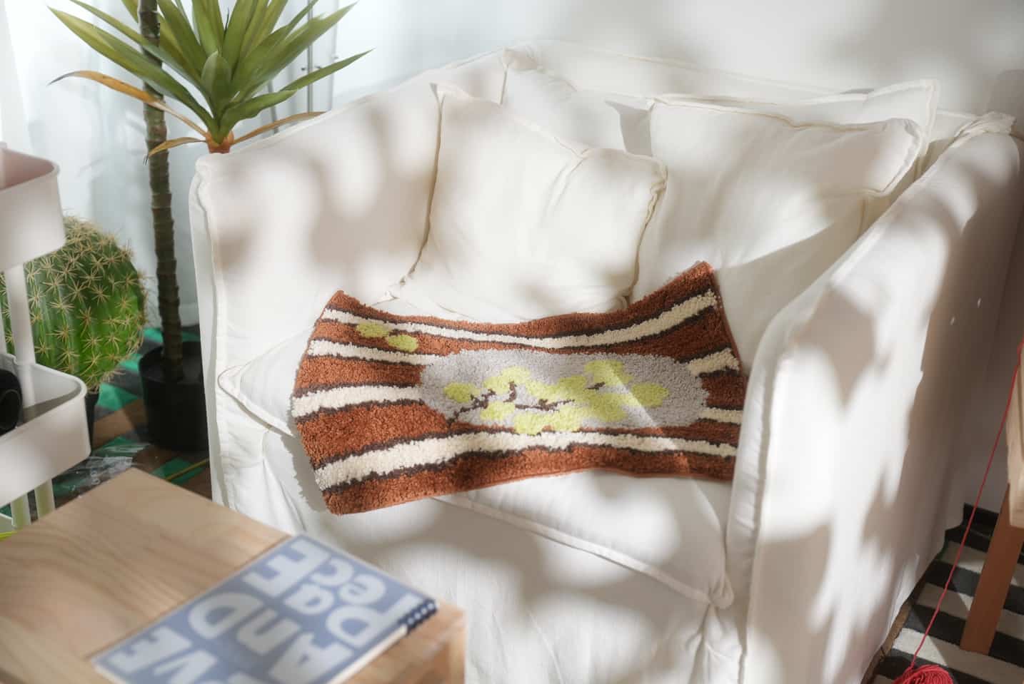 Handmade tufted rug with a brown and cream abstract pattern draped over a white armchair.