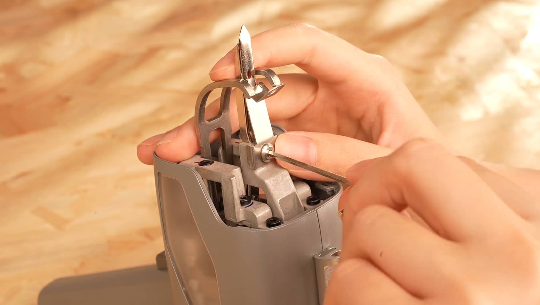 Close-up of hands adjusting the internal scissors/needle mechanism of a tufting gun