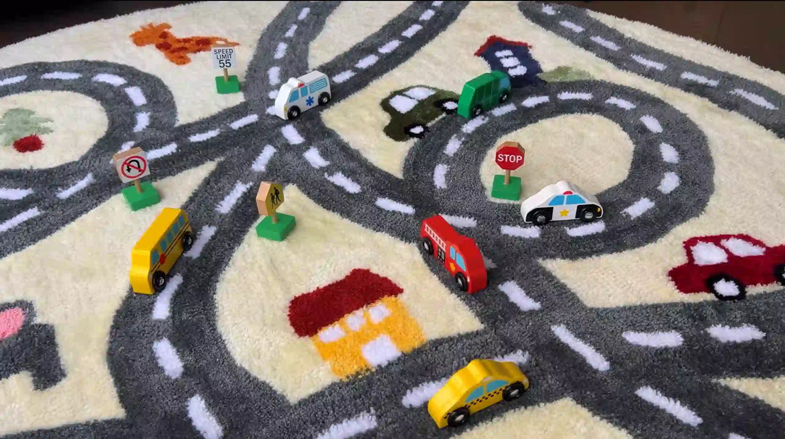 a colorful play mat with a road network design, featuring various toy vehicles and traffic signs to encourage imaginative play.