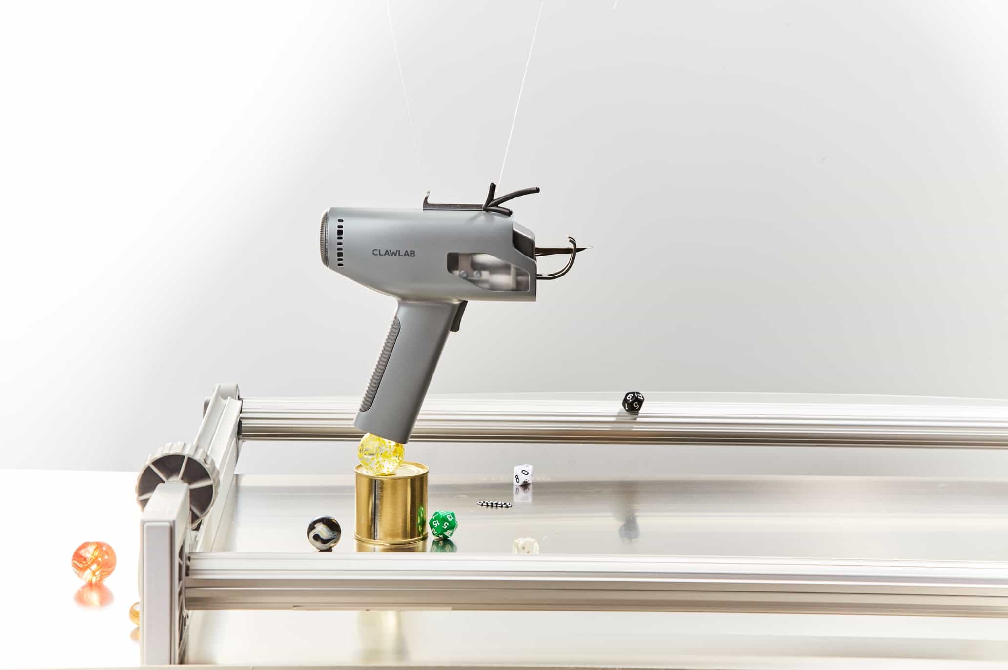 Grey Clawlab H1 electric tufting gun standing upright on a workspace, showcasing its sleek, enclosed design and lightweight ergonomic handle for rug making.